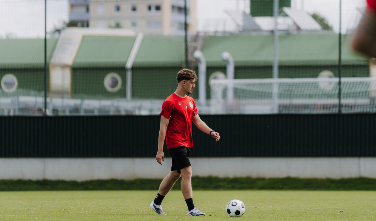 Fußballer im roten Trikot trainiert am Rasenplatz in Wien